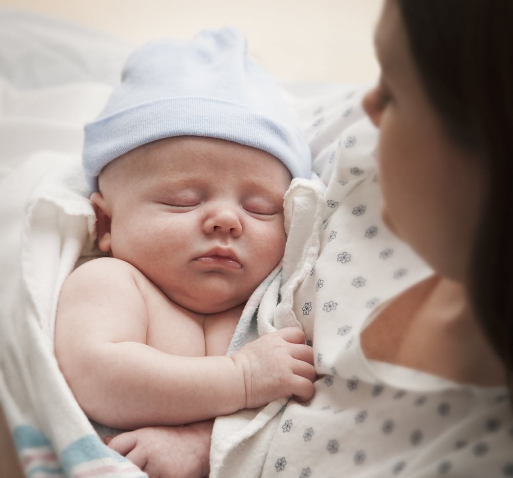 mom looking at newborn baby, marveling at the cost of giving birth