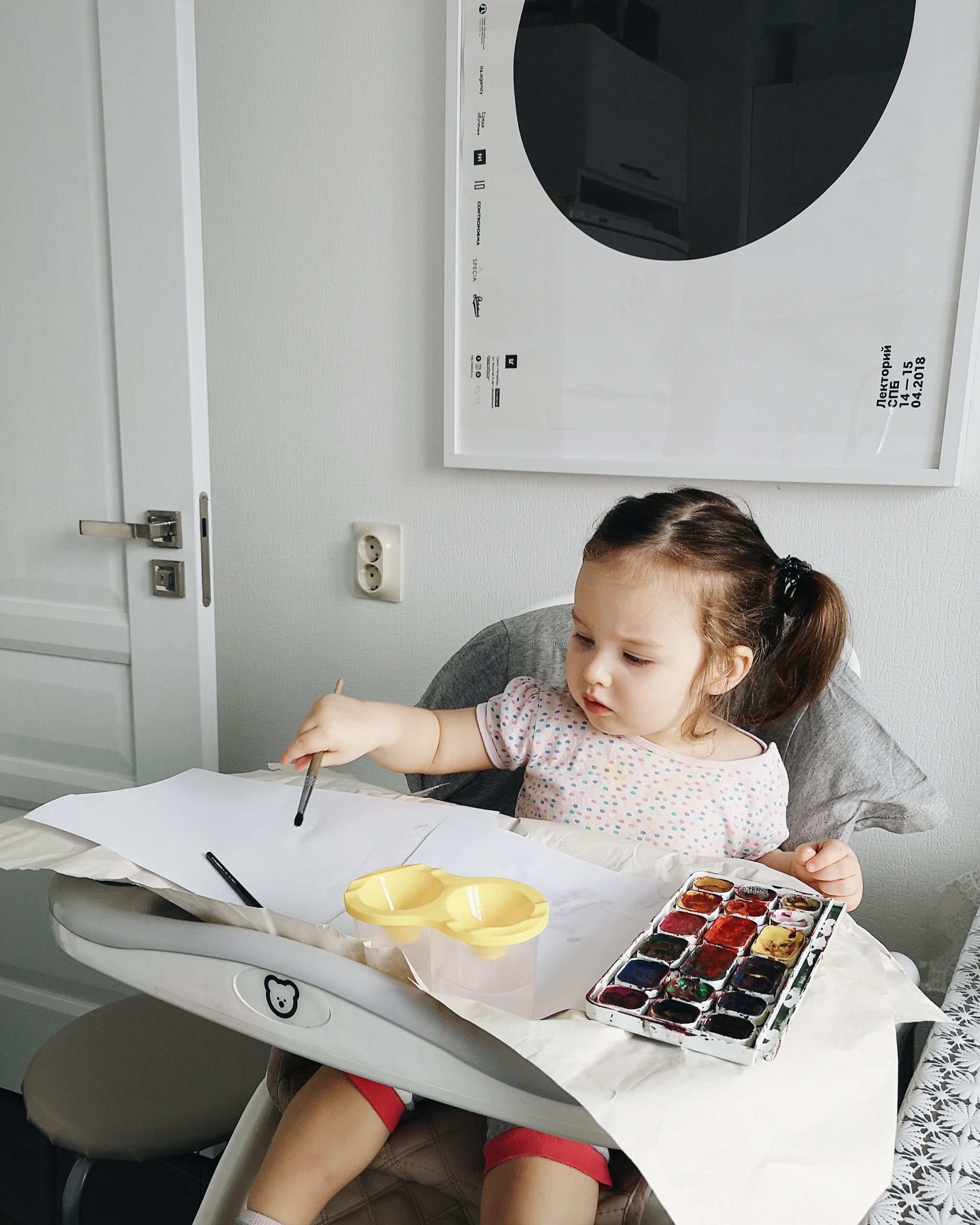 little girl playing with paint in a high chair