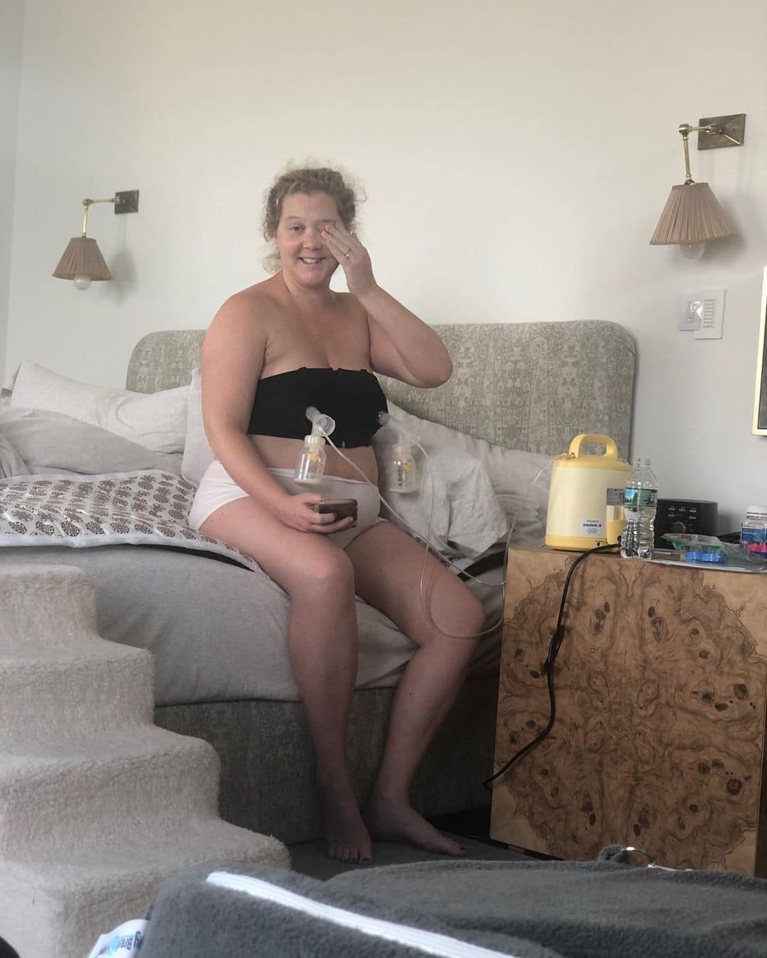 Amy Schumer pumping on the edge of her bed
