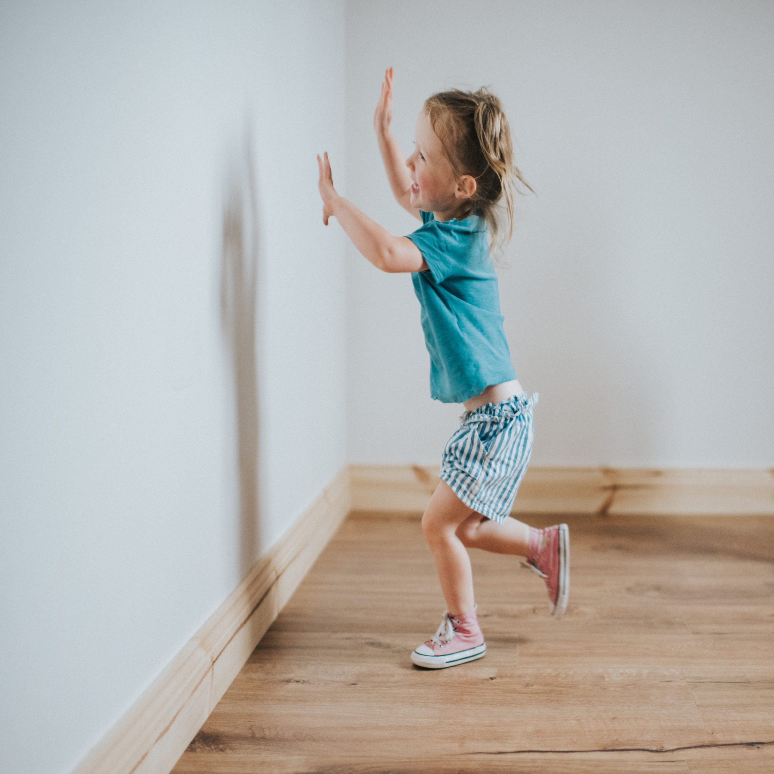 child running towards wall with hands up