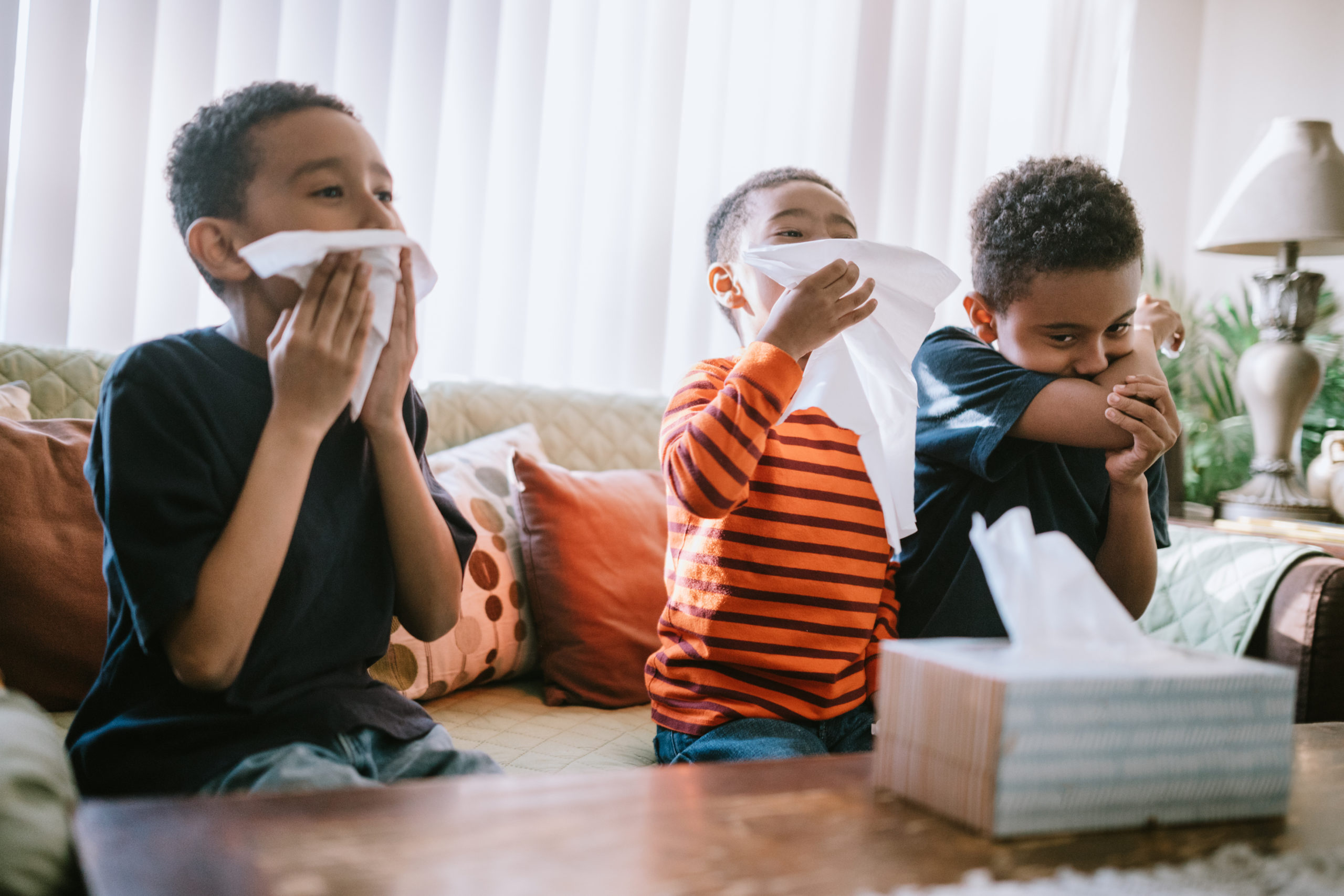 three kids blowing their noses