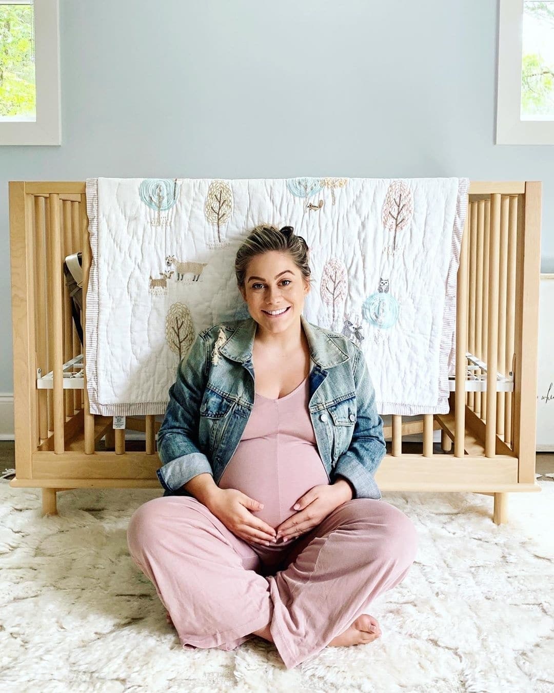 pregnant Shawn Johnson East sitting in front of a crib