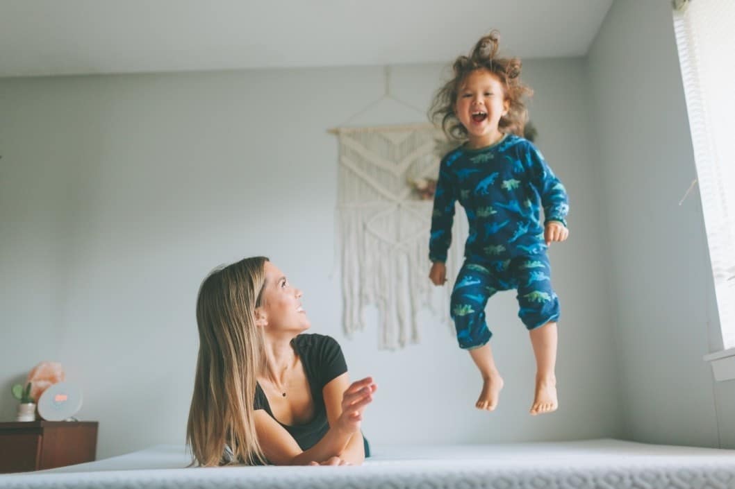 mom watching toddler jump on the bed