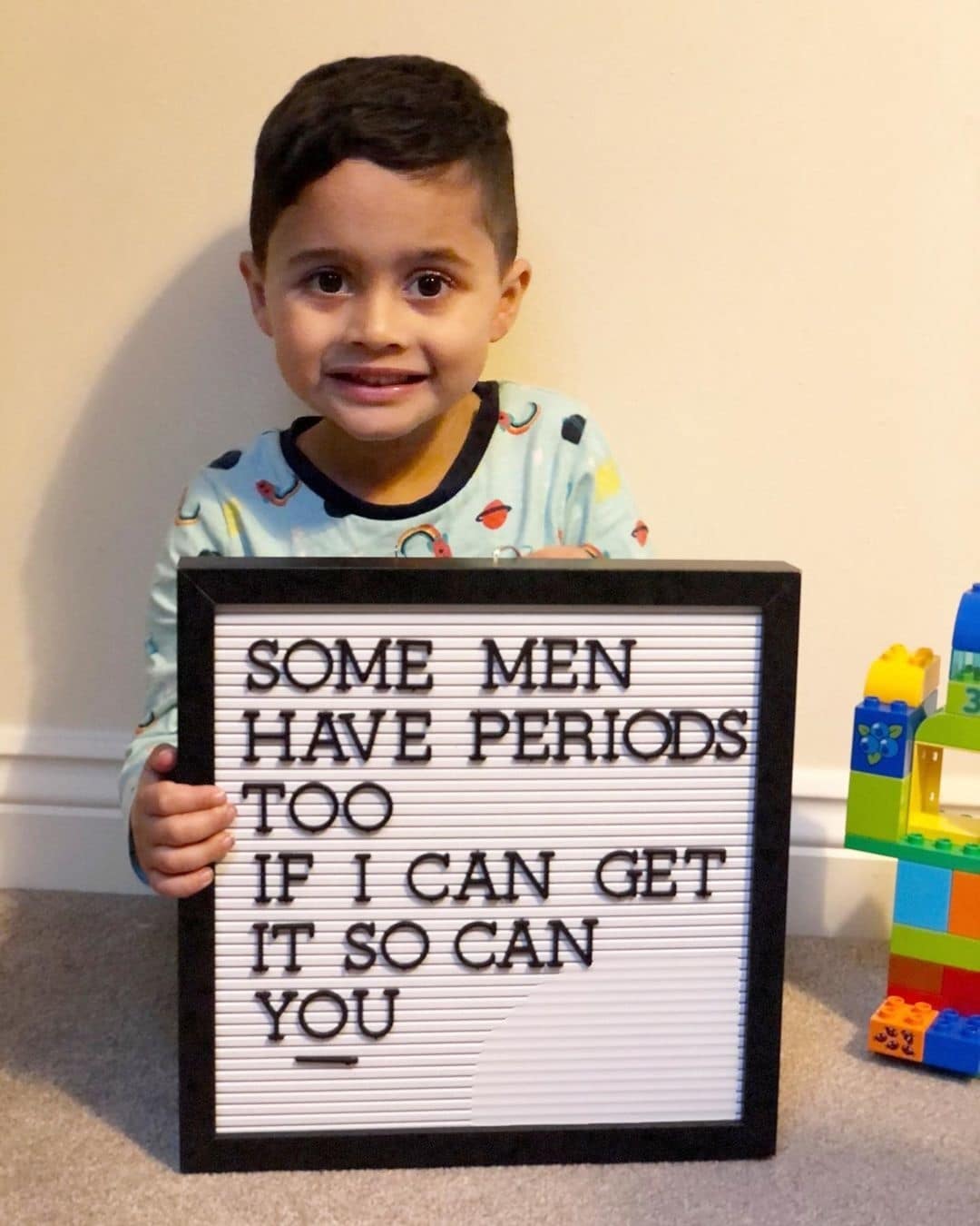 little boy holding a letterboard sign