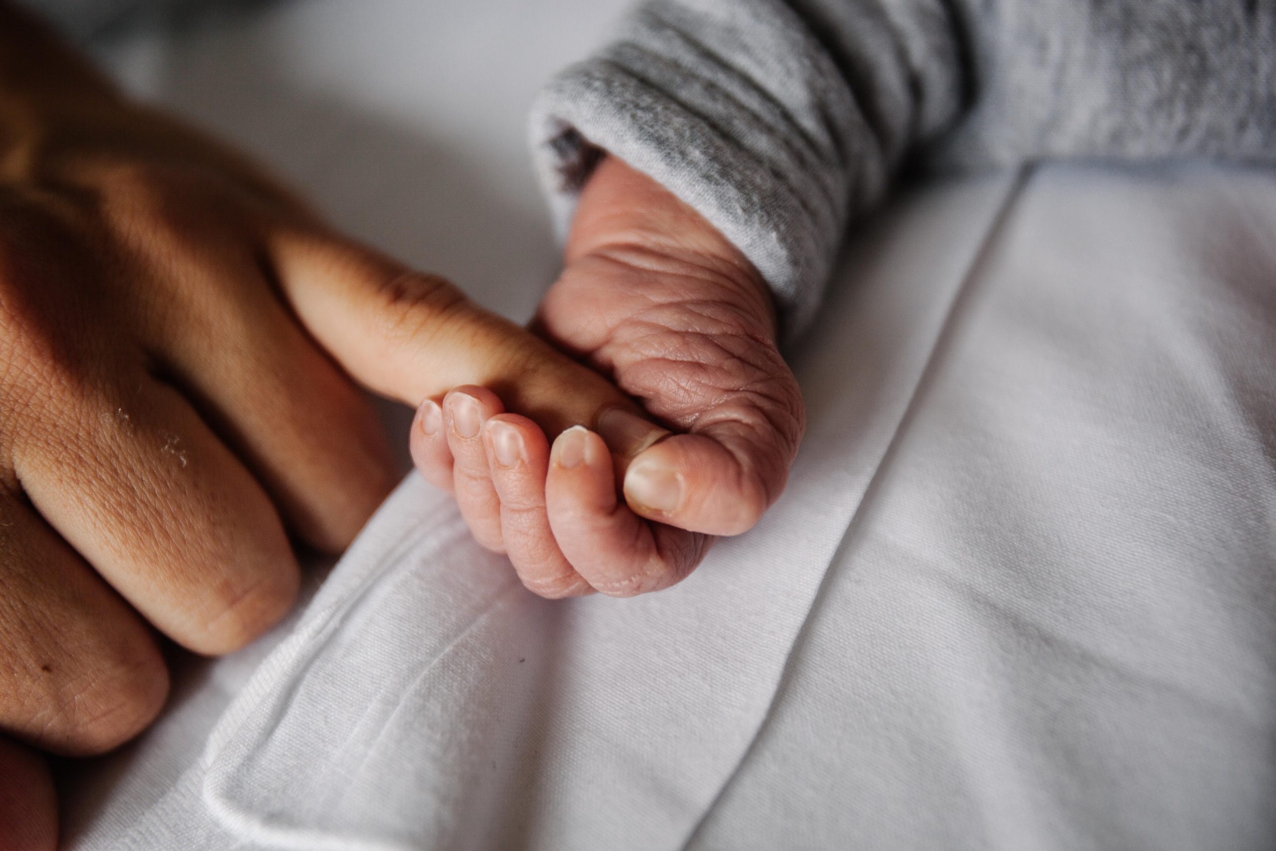 baby holding moms finger