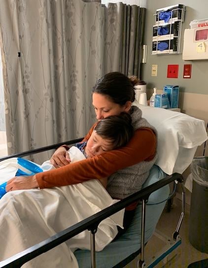 mom working in a hospital bed holding her son