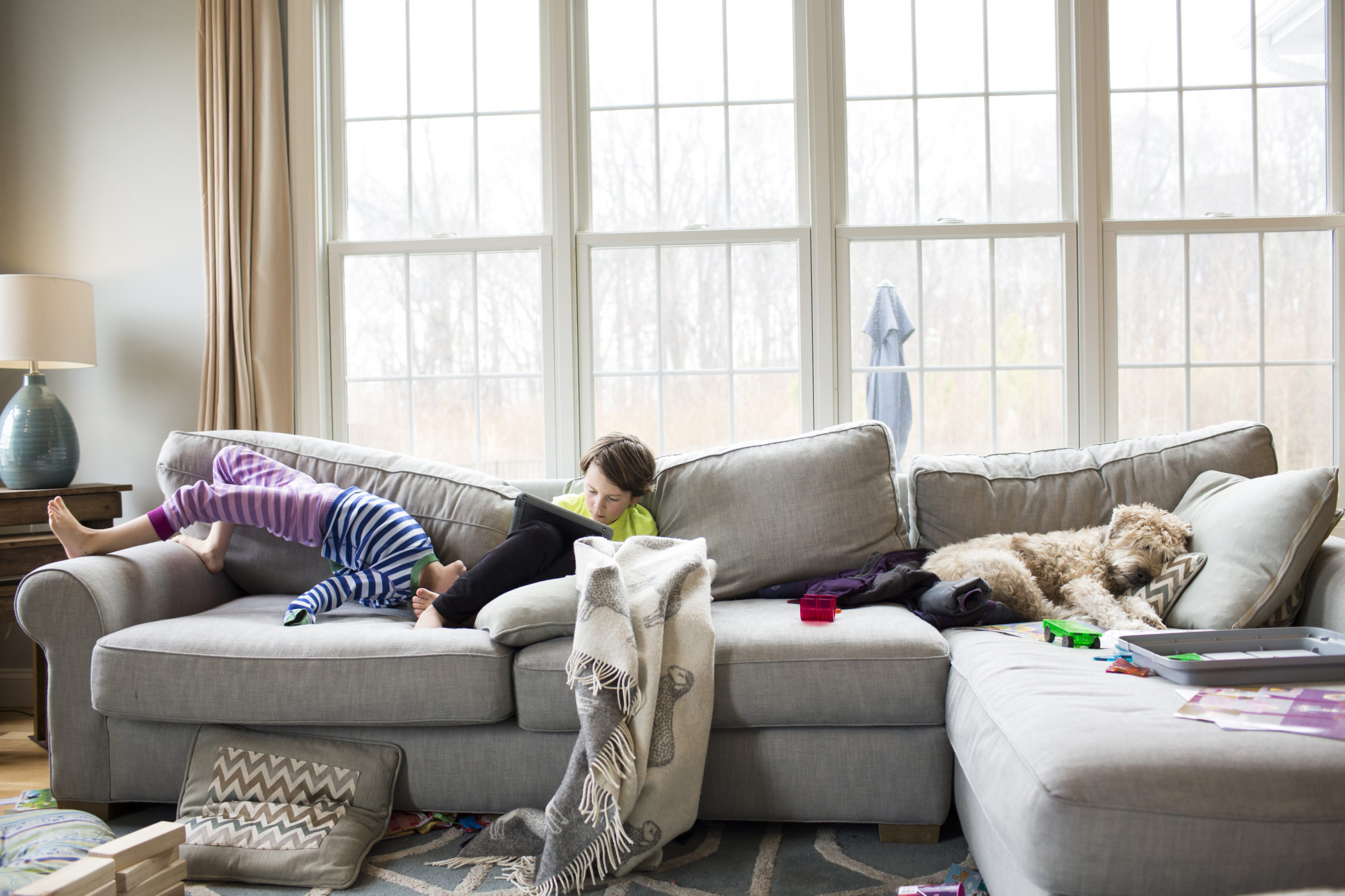 one child on ipad, one child playing on couch, & dog sleeping on couch- how to declutter your life