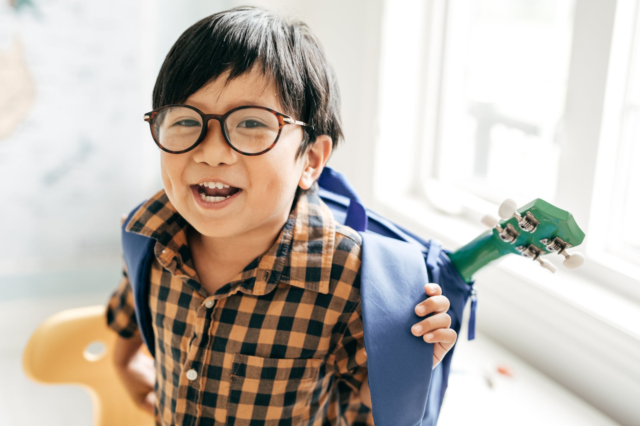 little boy putting on backpack