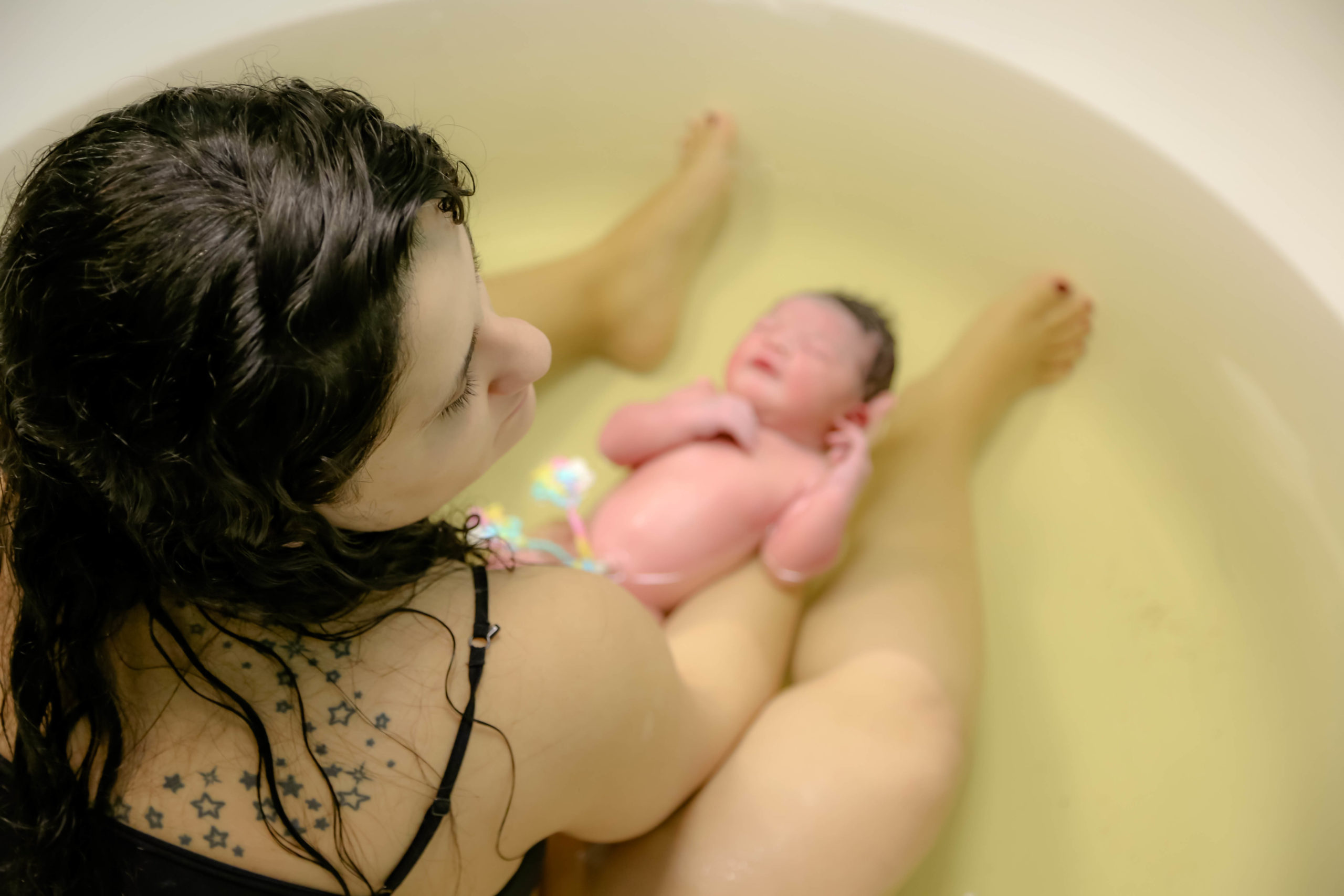 mom holding baby in a pool after water birth