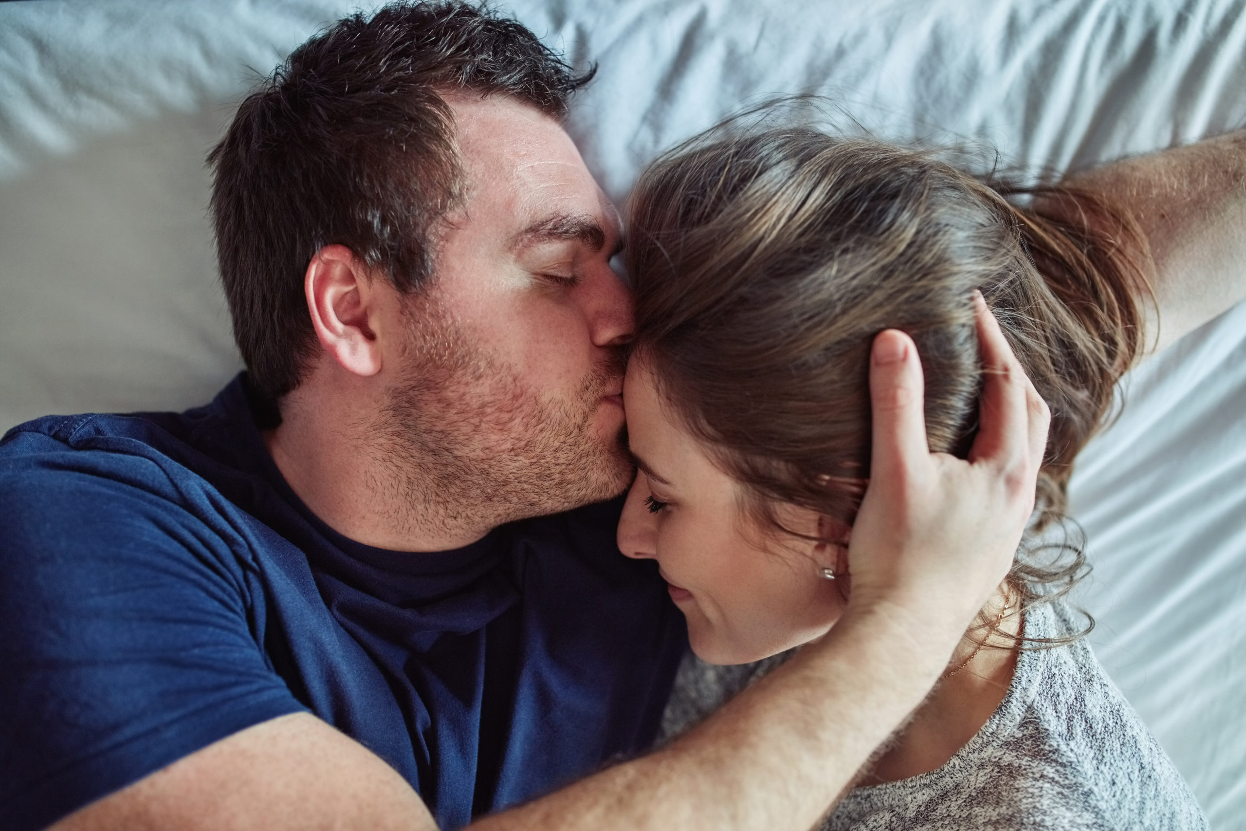 man kissing woman on the forehead