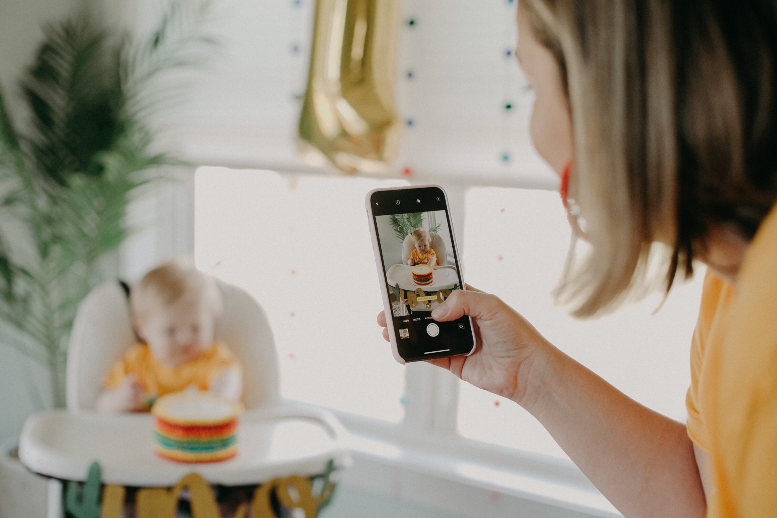 mom taking a picture of baby sitting in a high chair