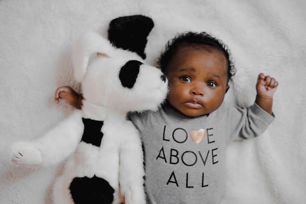 baby laying next to a stuffed animal