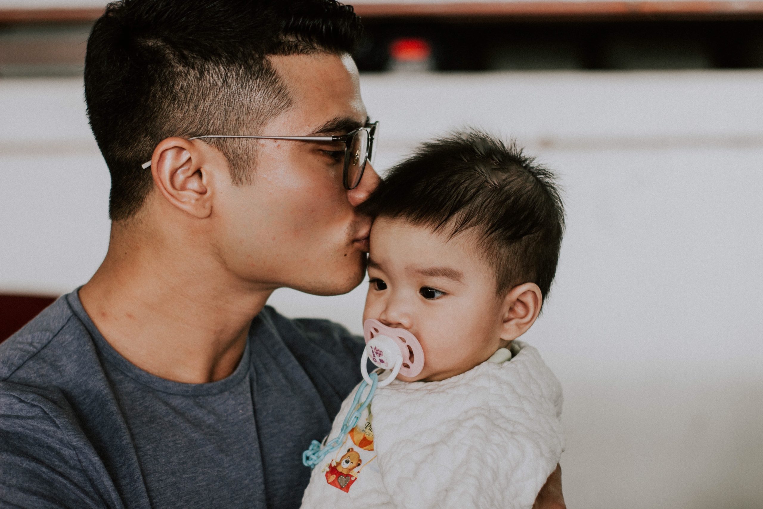 father kissing head of his infant