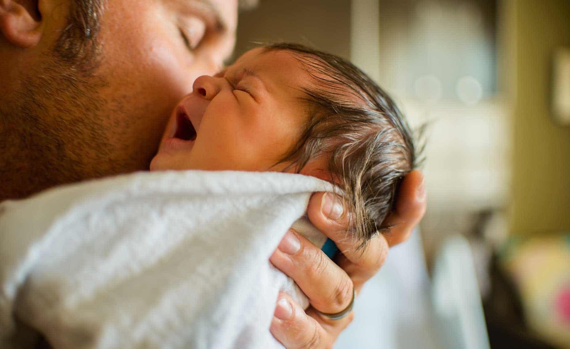 dad kissing newborn baby