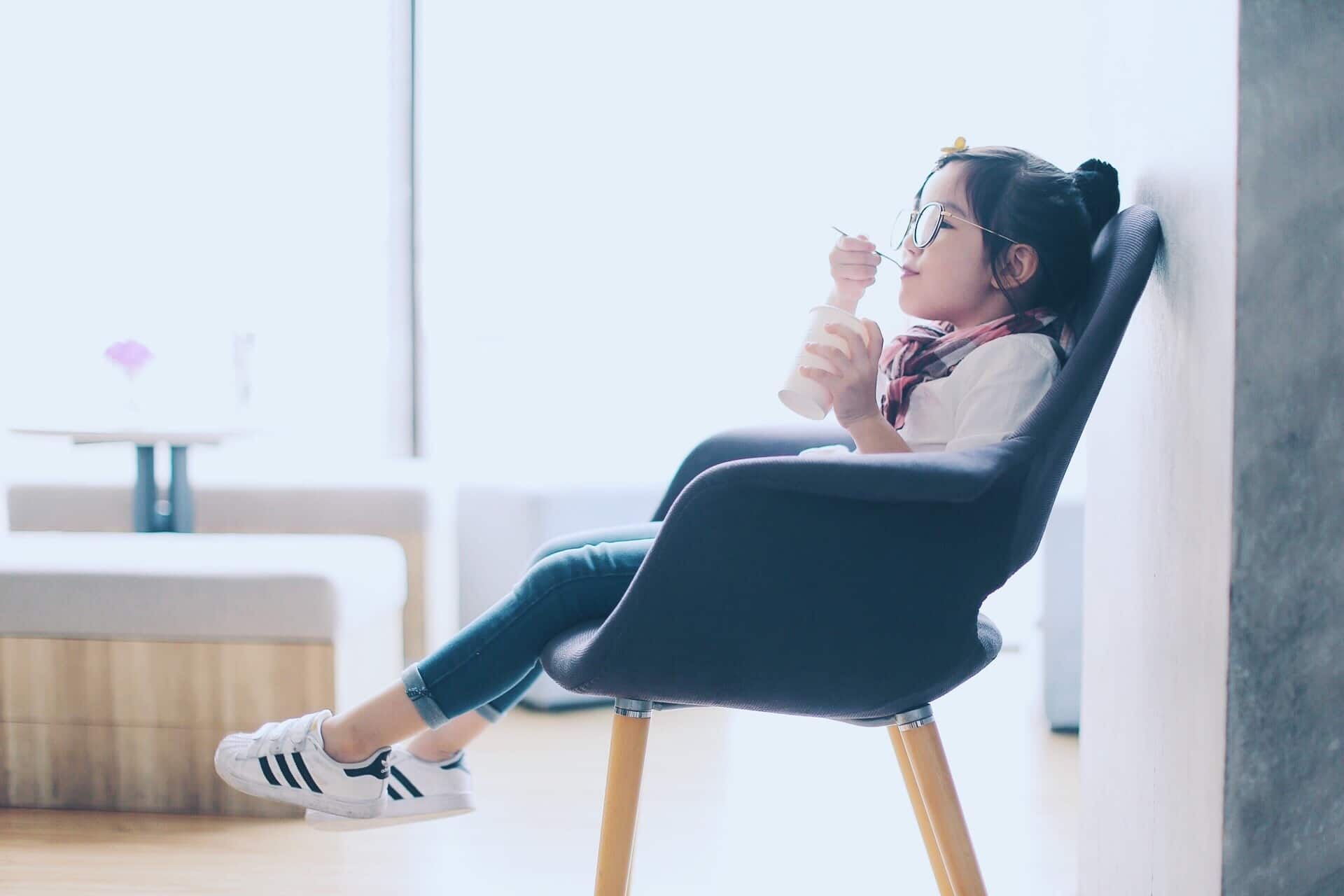 little girl sitting in a chair eating