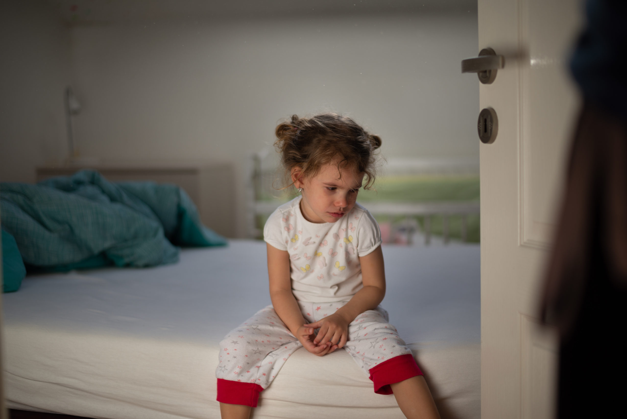 toddler sitting on the edge of a bed