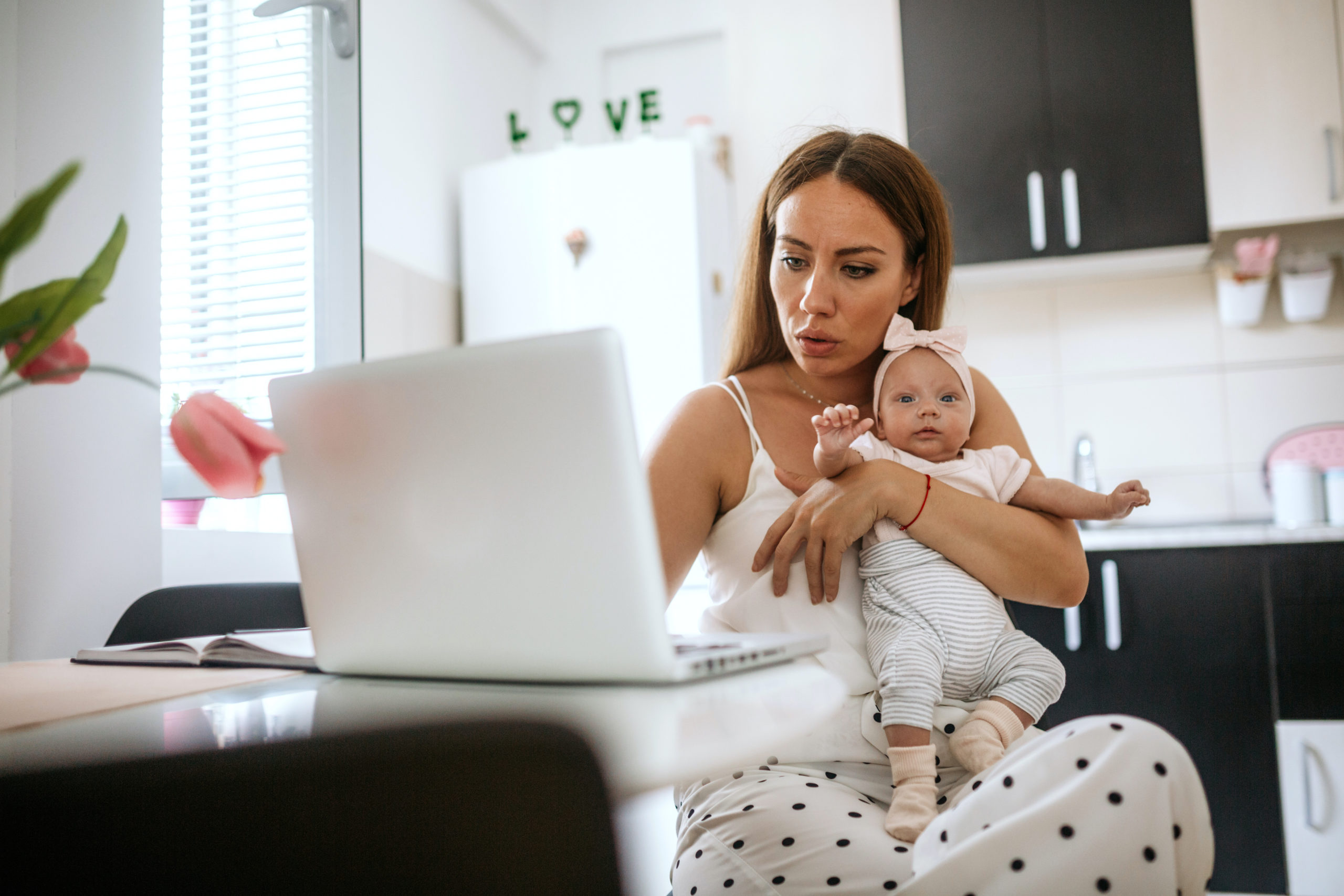 mom holding baby while working on a computer