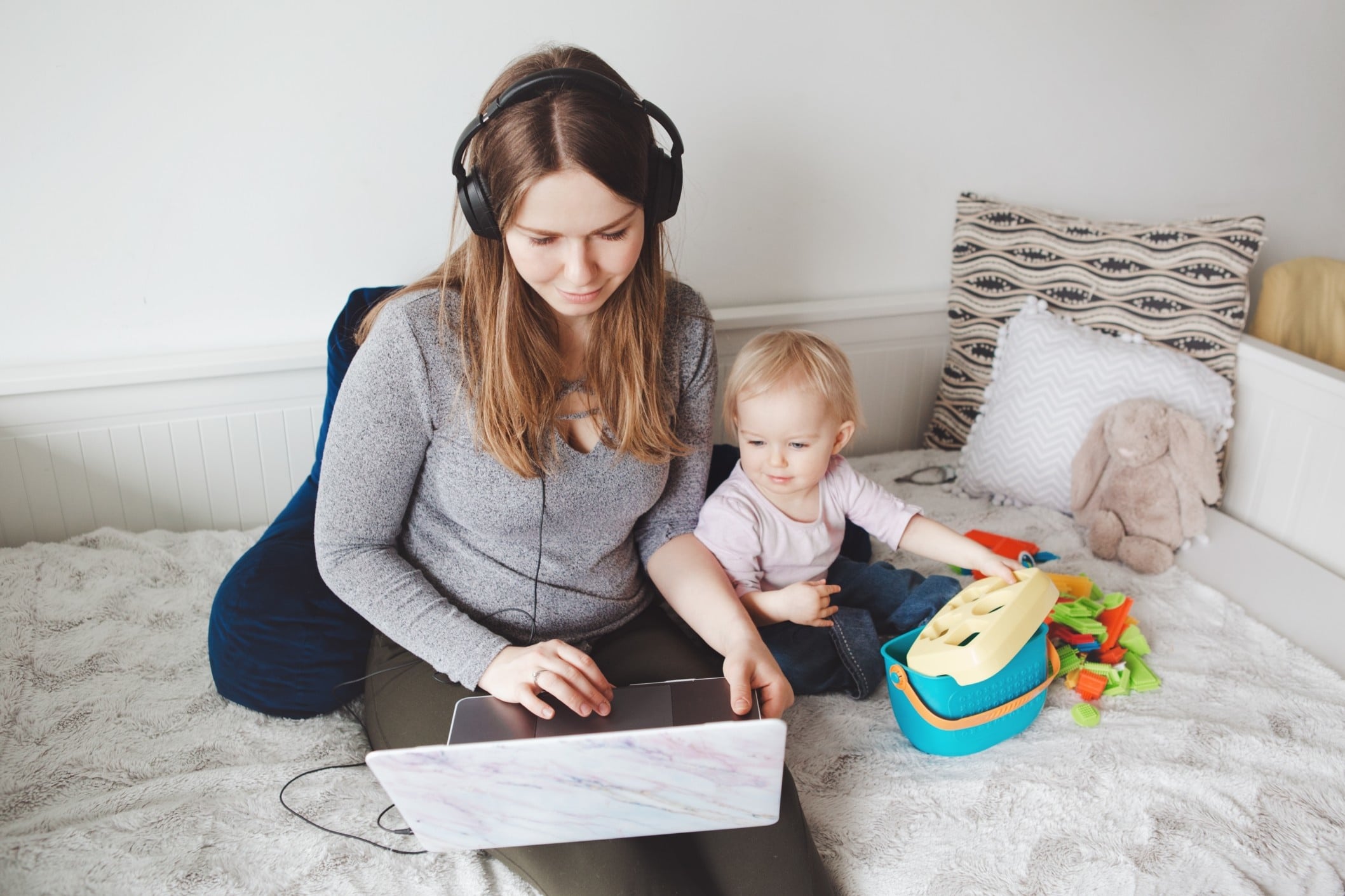 mom working on a computer while toddler sits beside her