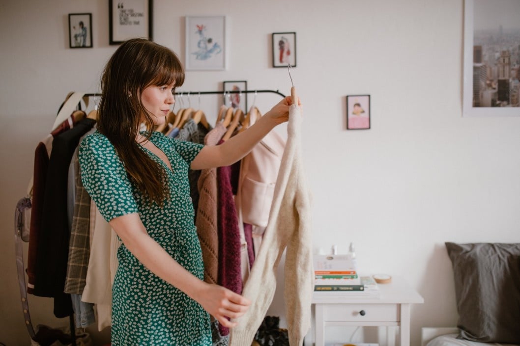 woman picking out a dress from a rack of clothes