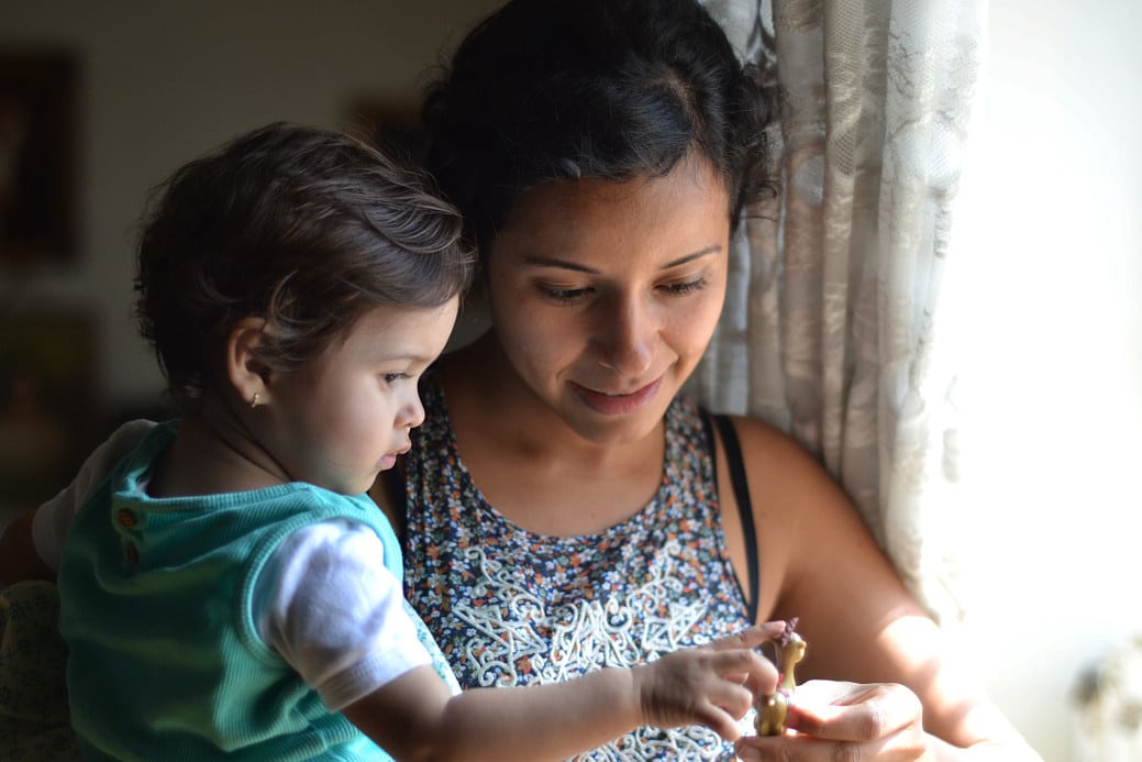 mom holding daughter next to a window