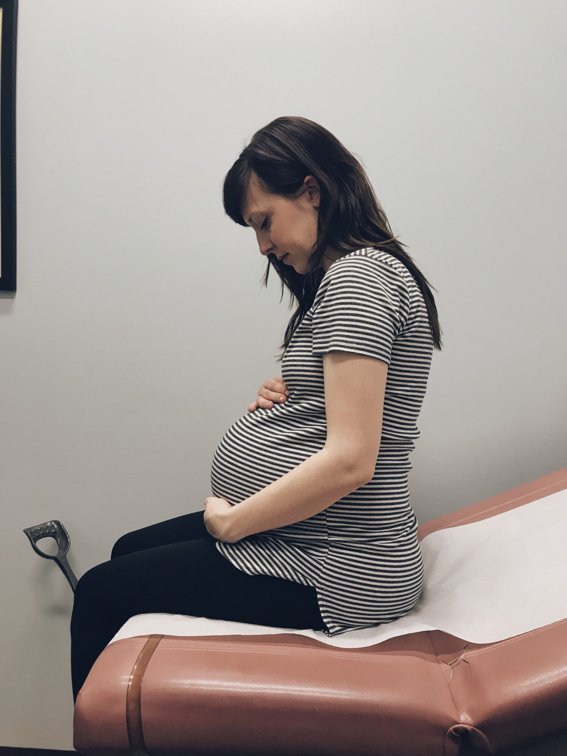 pregnant woman holding belly at a doctors office