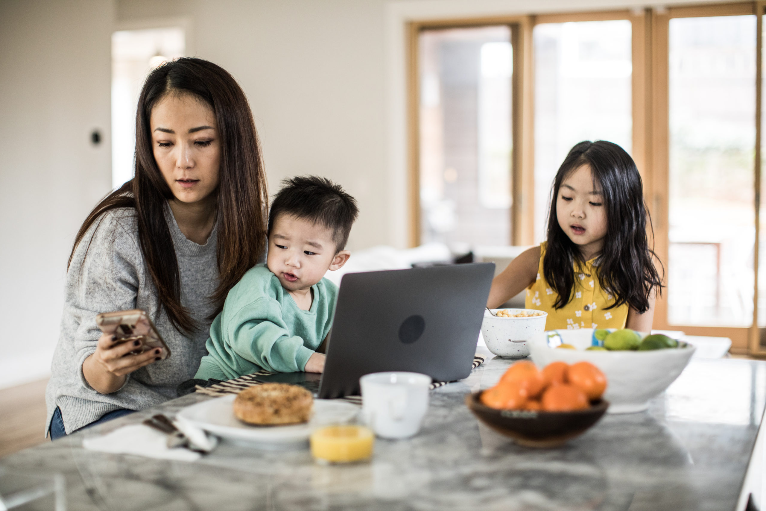 mom working while two kids eat breakfast