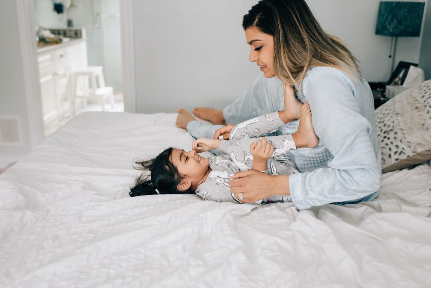 mom playing with daughter on the bed