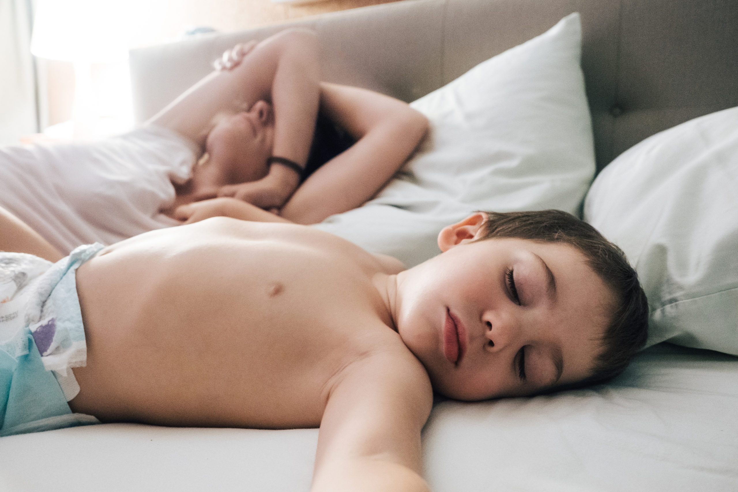 little boy sleeping in bed next to mom