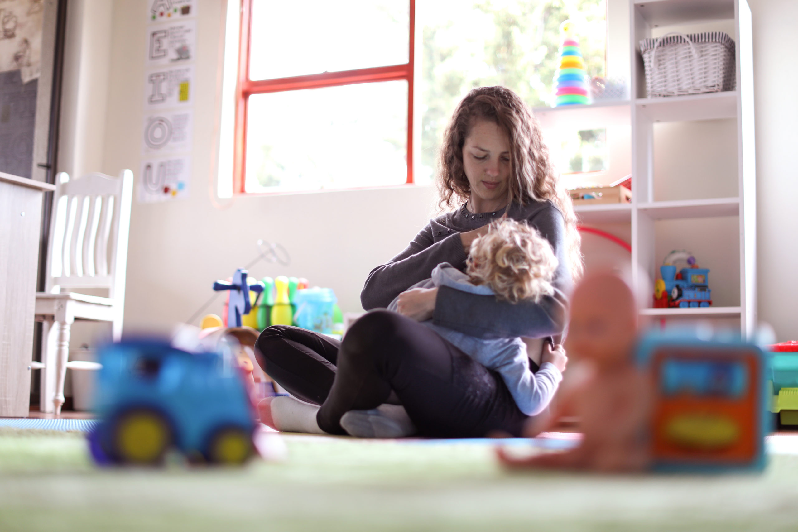 mom breastfeeding toddler in the play room