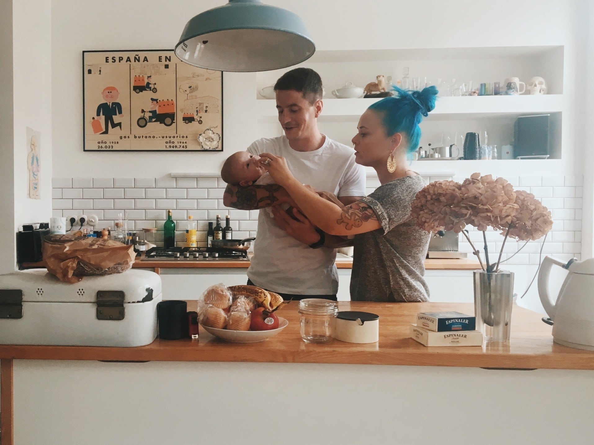 parents looking over a newborn baby standing in their kitchen