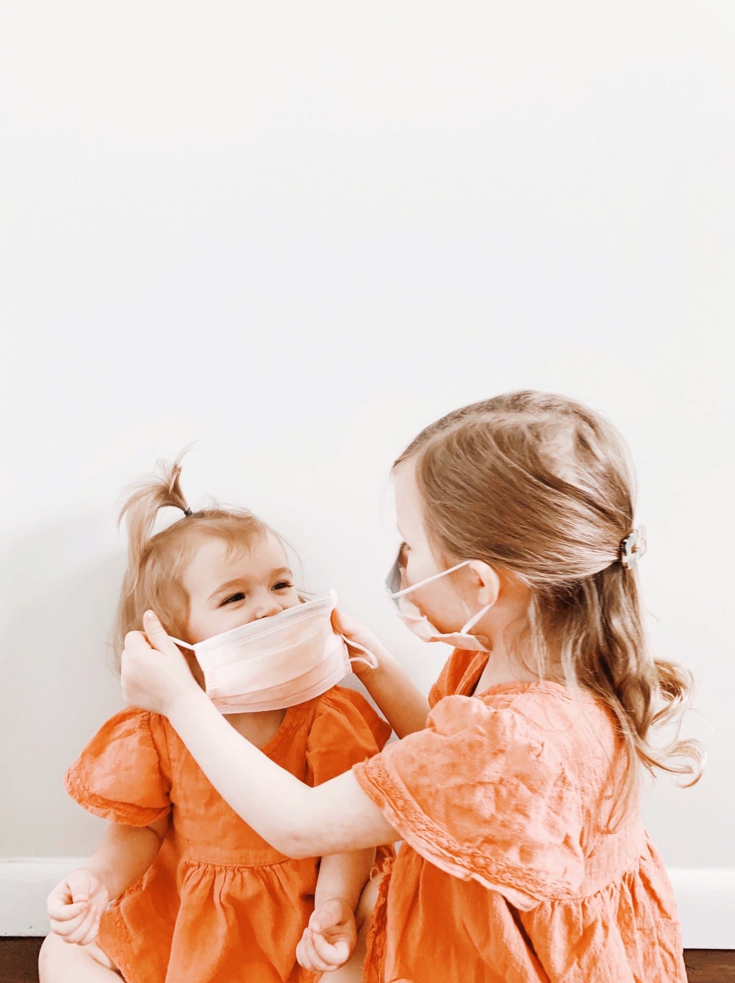 child helping another child put on a mask