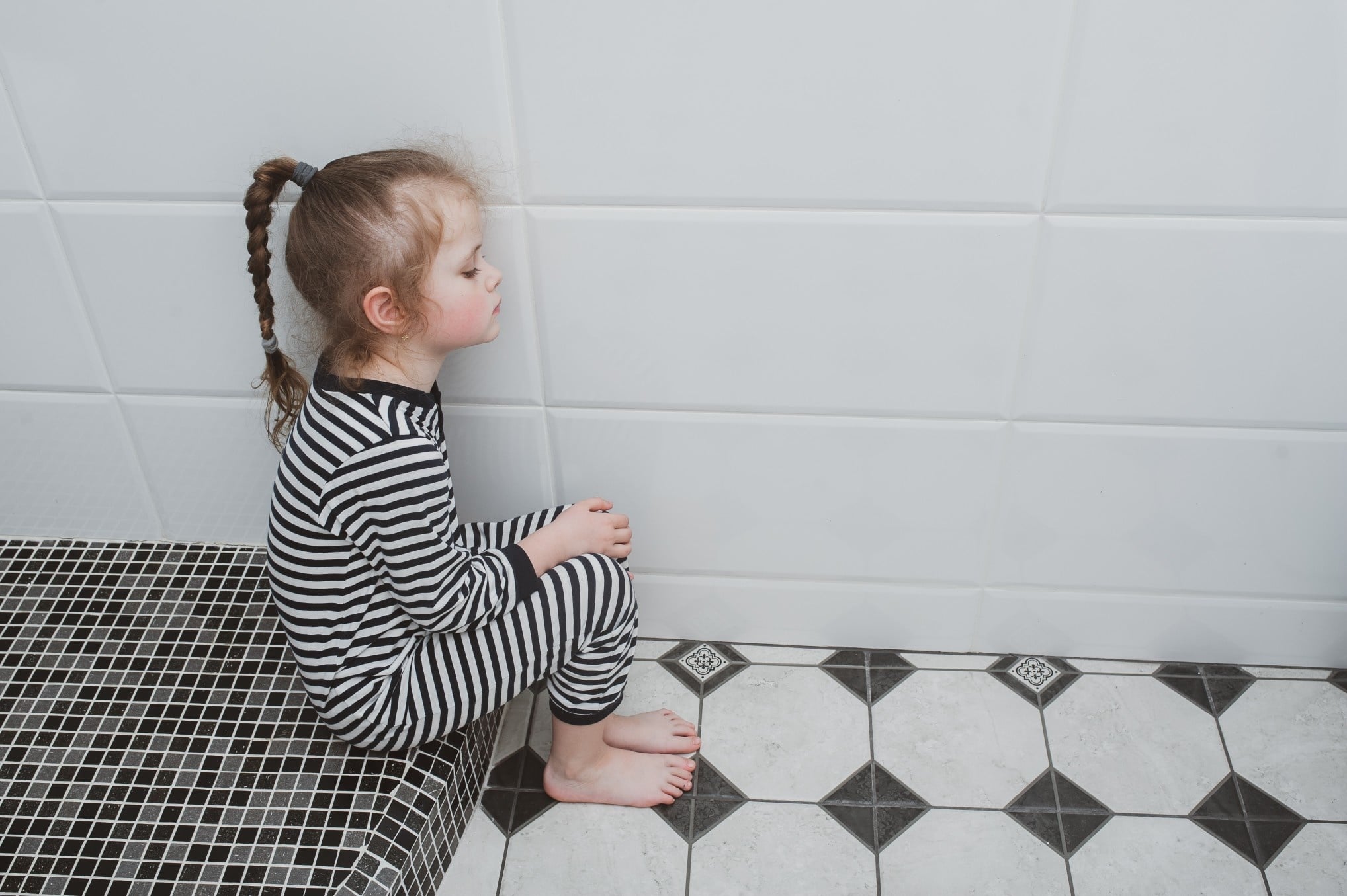 little girl sitting on the bathroom floor