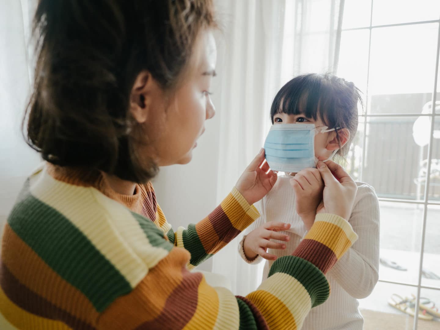 mom helping child put on a mask