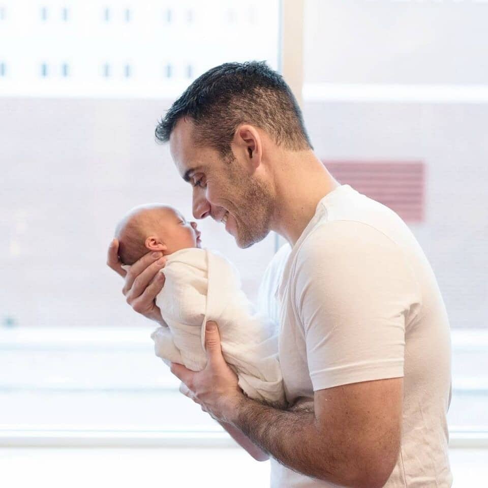 father holding a swaddled newborn baby to his face