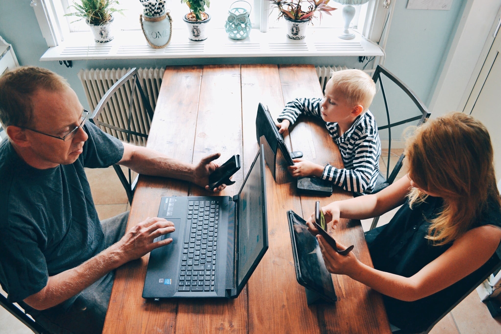 parents and kid working virtually at a table