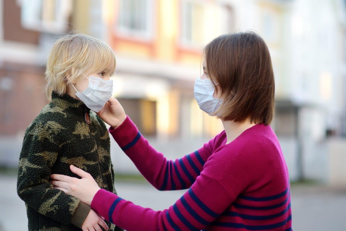 mom helping a little boy put on a mask