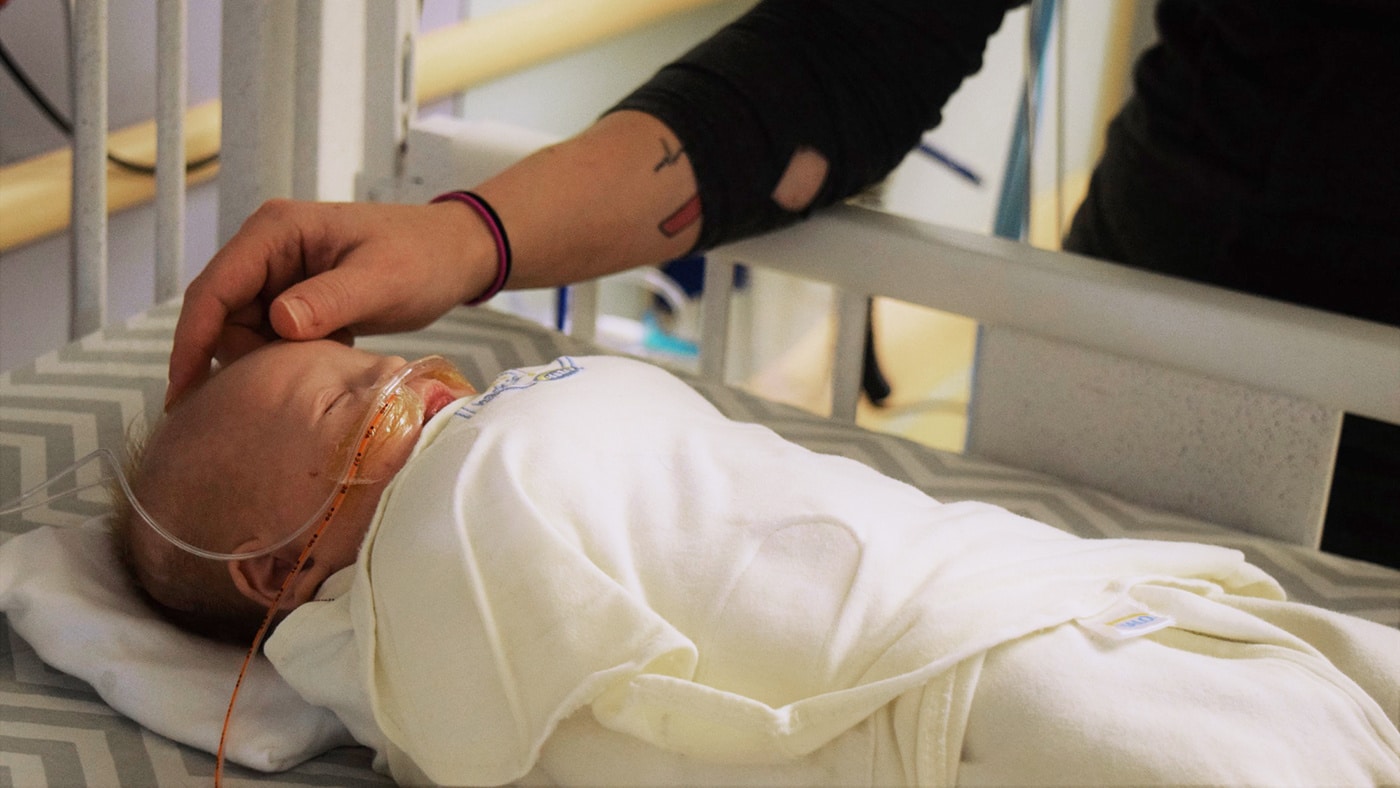 mom comforting newborn in the NICU