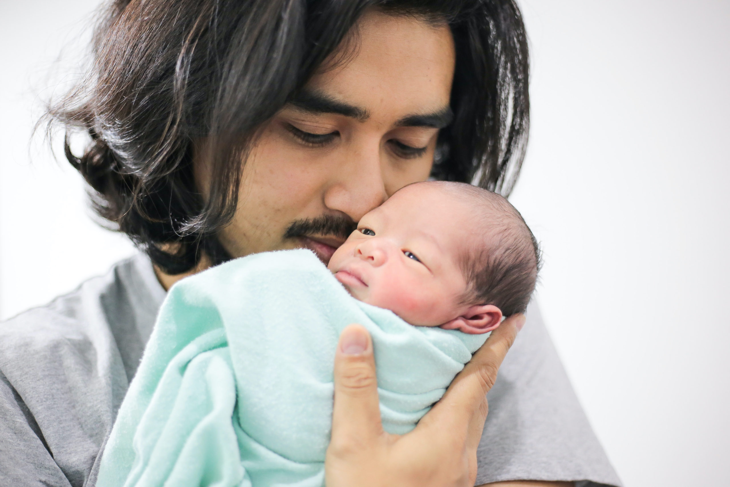 dad kissing newborn baby