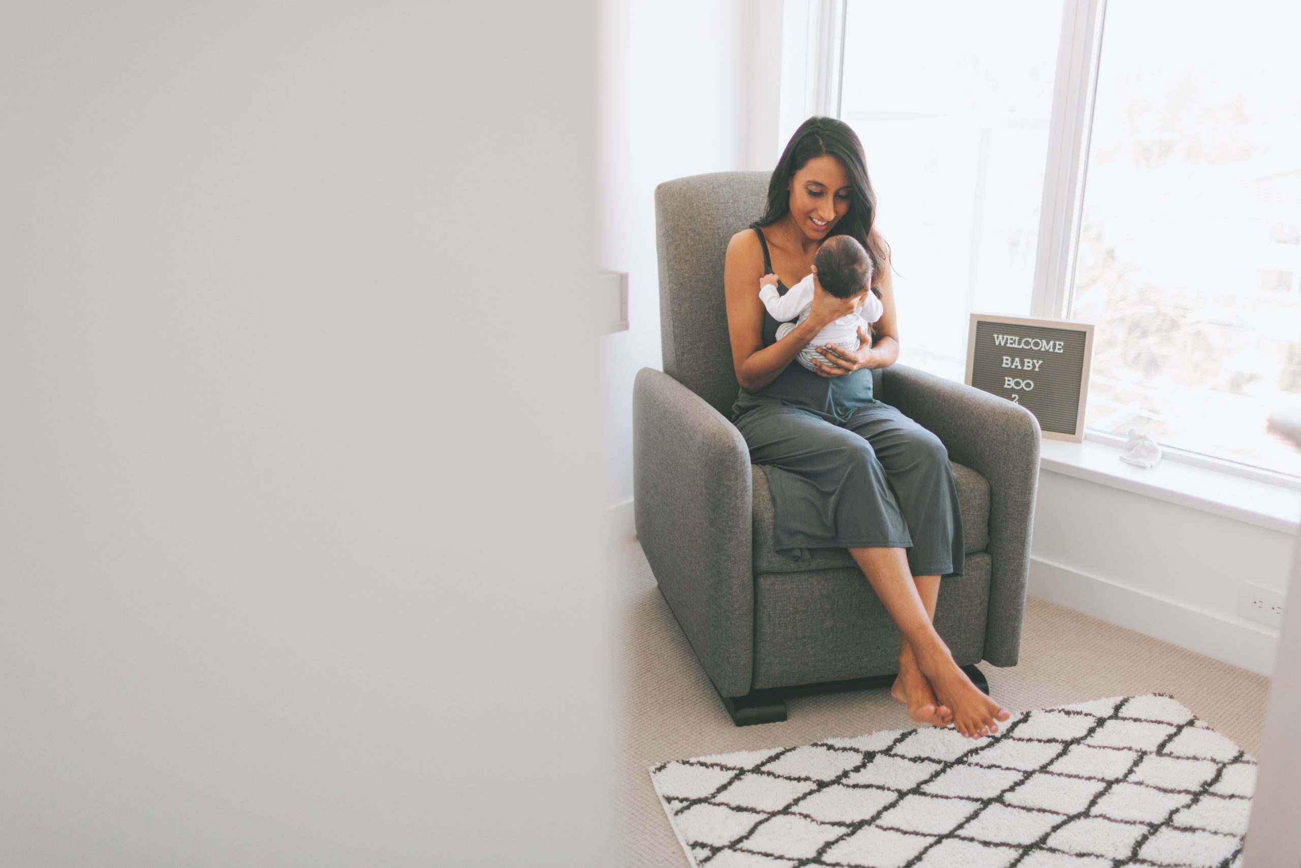 mom rocking newborn baby in a glider