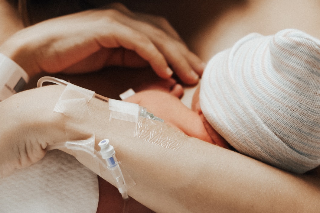 mom with an IV holding newborn baby after giving birth in her sleep