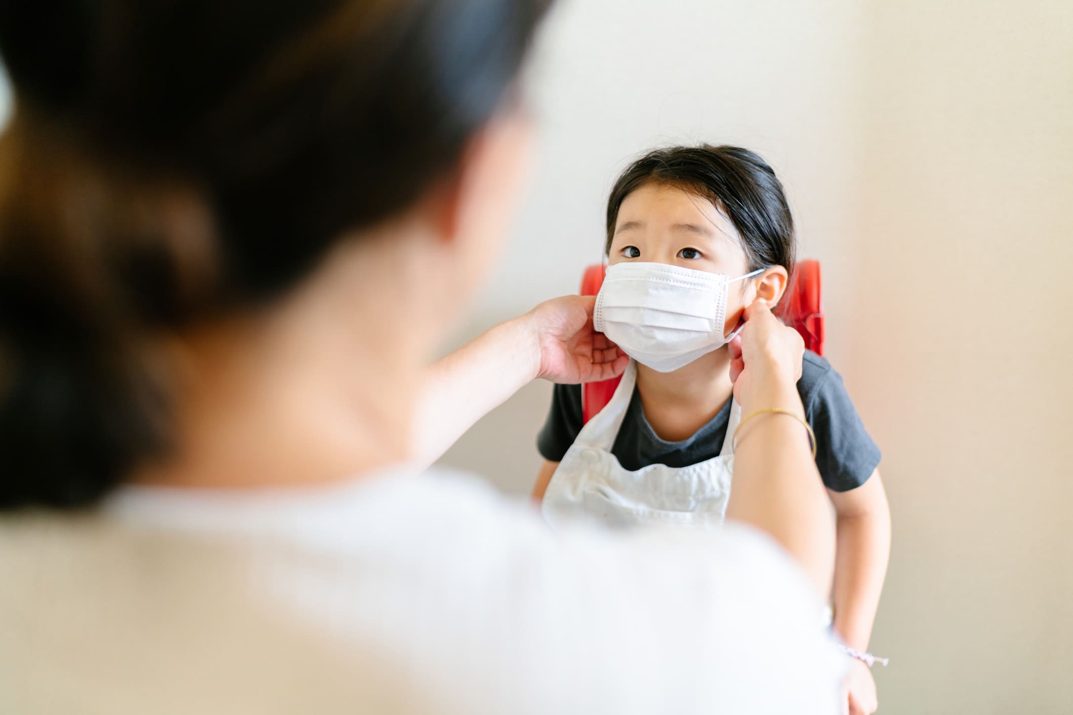 mom helping a child put on a mask