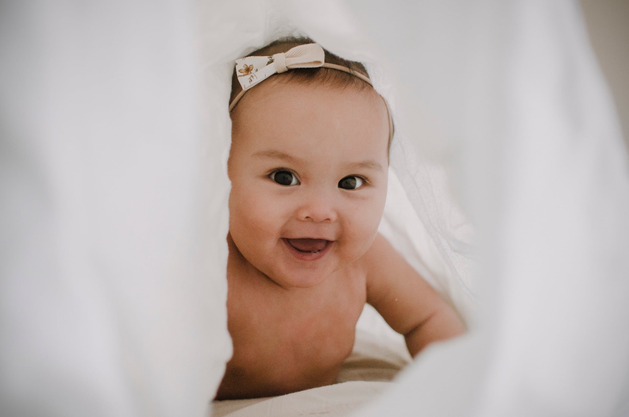 cute baby smiling under a sheet- baby names that means thankful