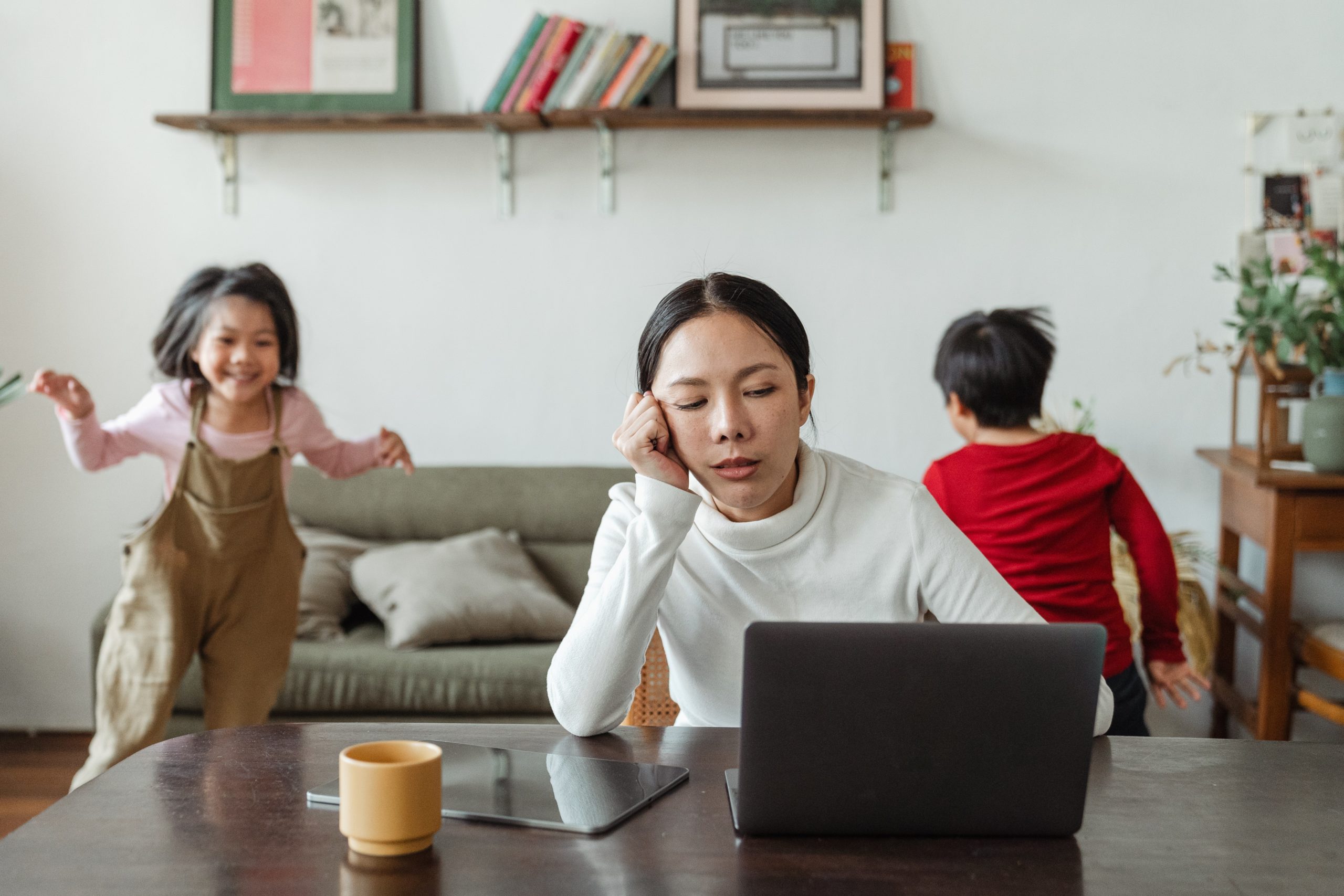 mom working with two kids playing behind her