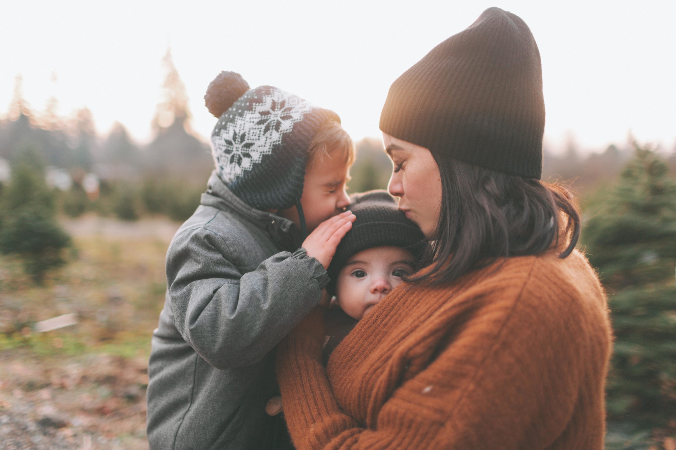 mom kissing two son on top of the head