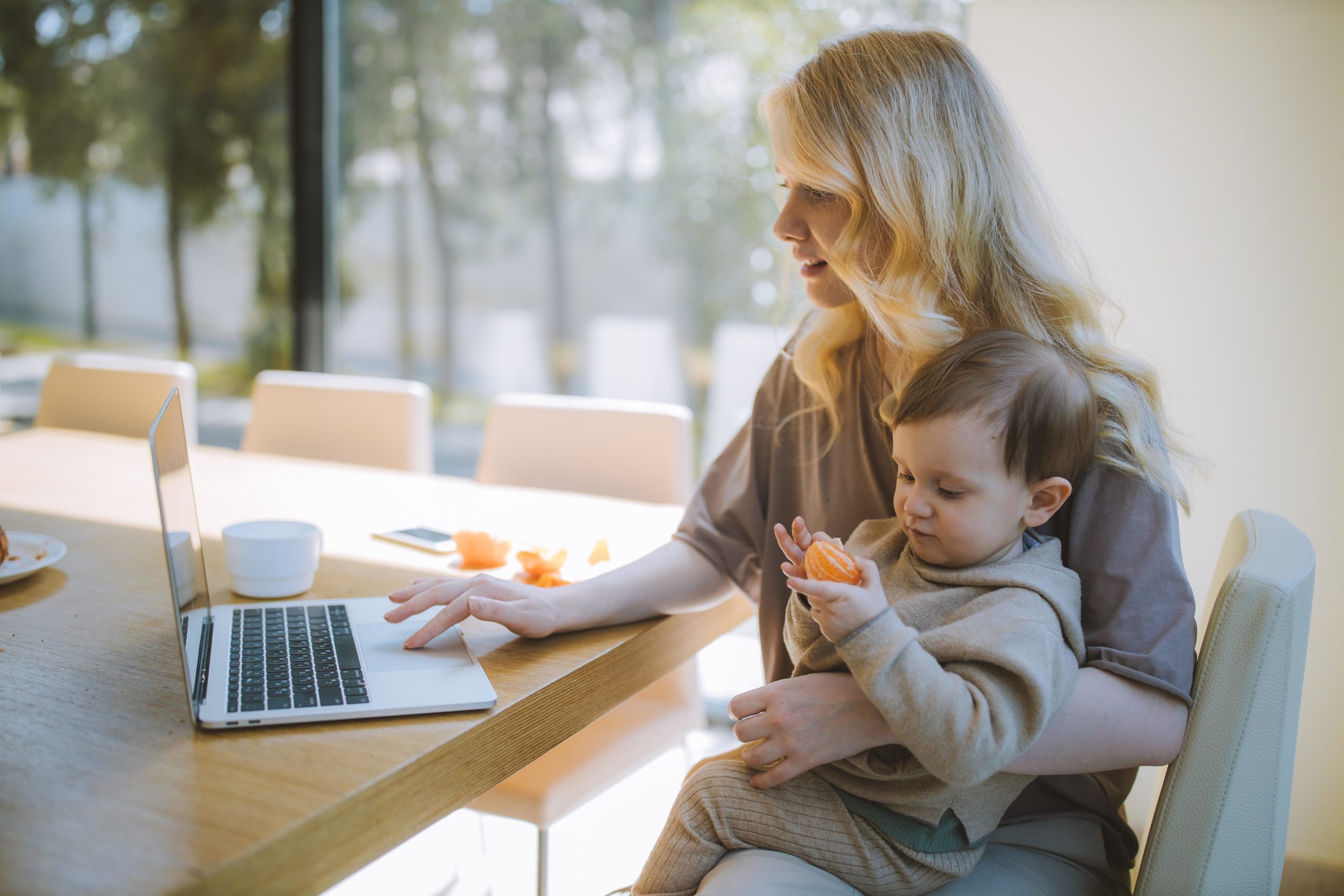 mom on a laptop with baby in her lap