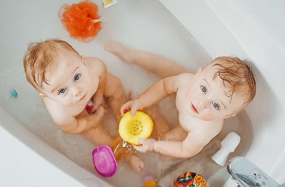 twin-babies-in-a-tub-looking-at-the-camera