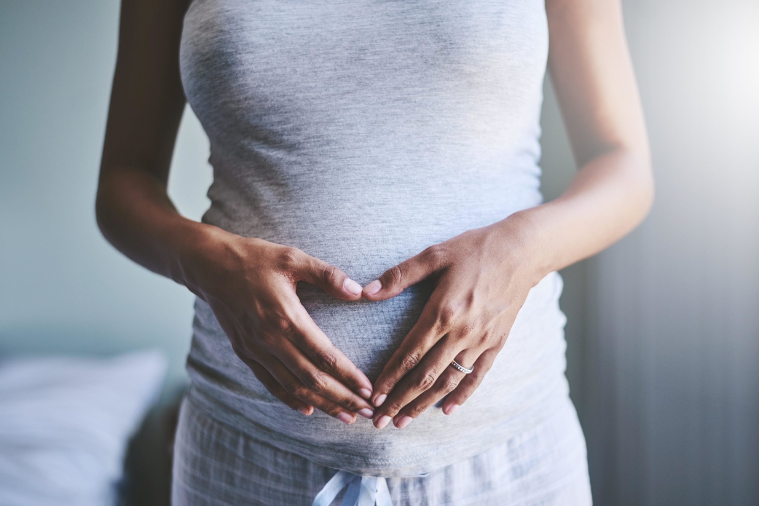 pregnant woman forming a heart with her hands in front of her pregnant belly