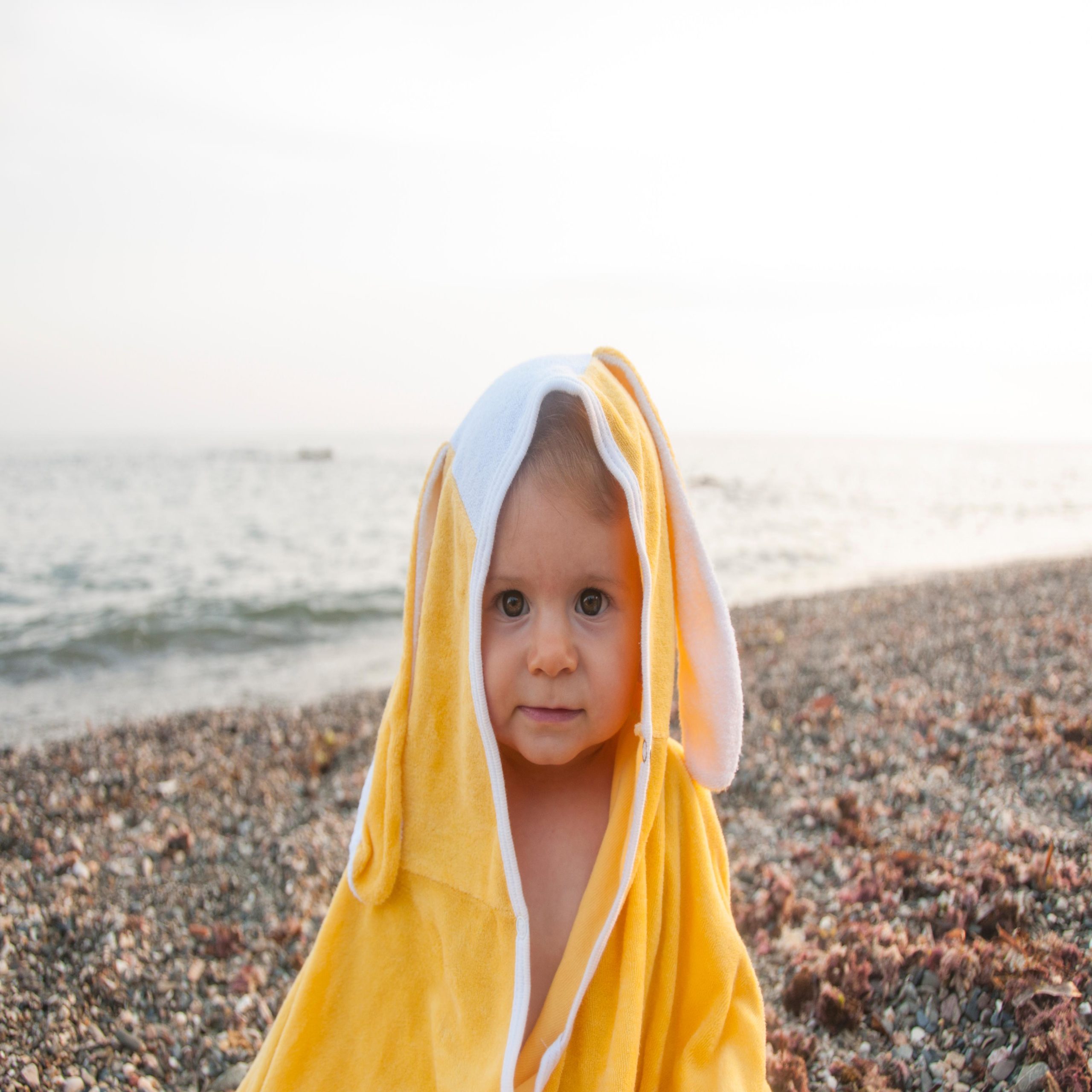 child wearing yellow and white towel at the beach- aquarius names