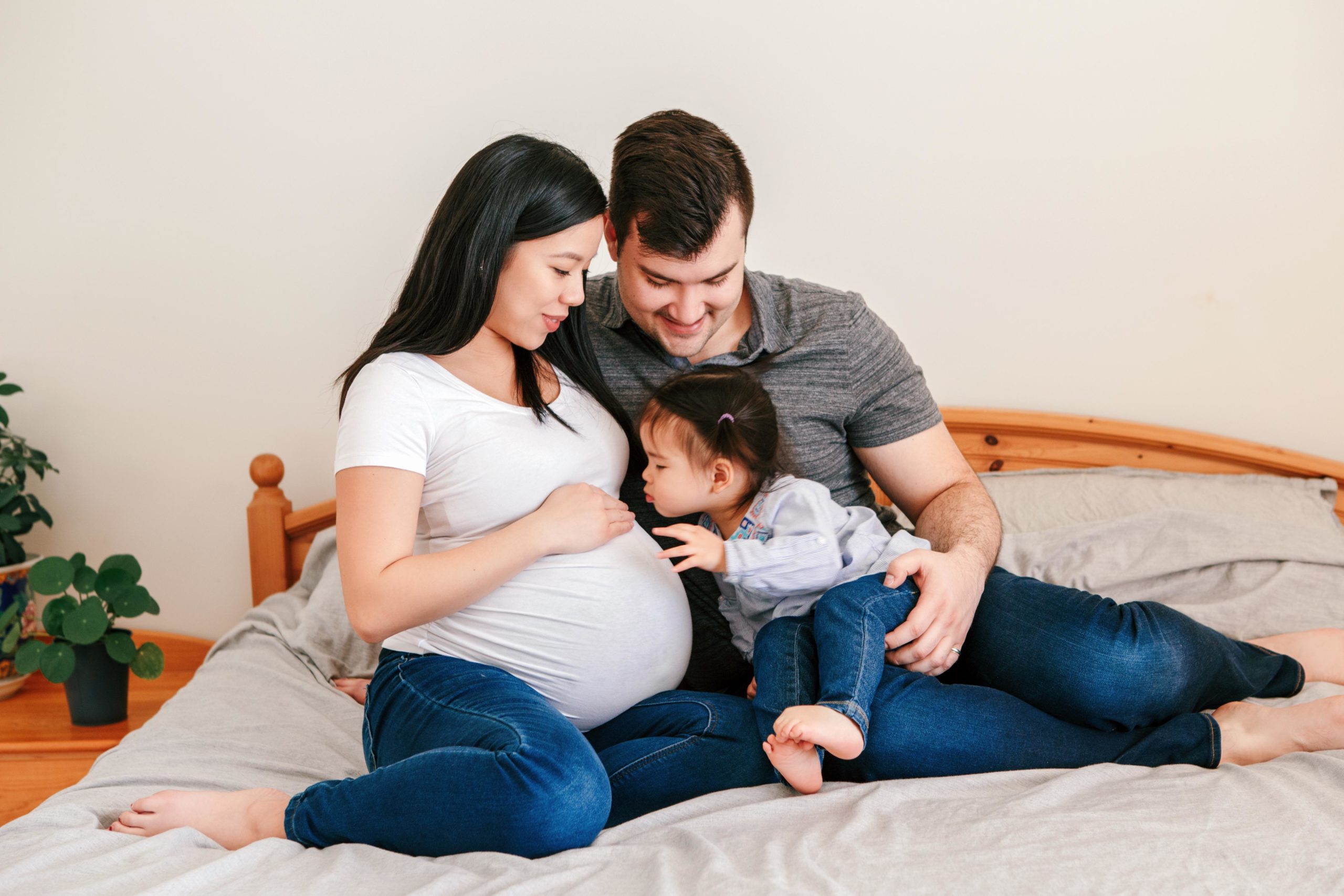 baby kissing moms pregnant belly as dad sits behind