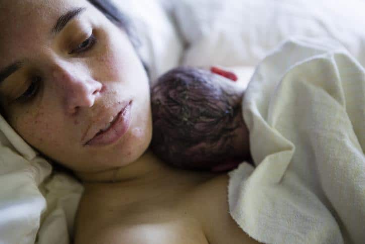 mom holding newborn in bed - postpartum shaking